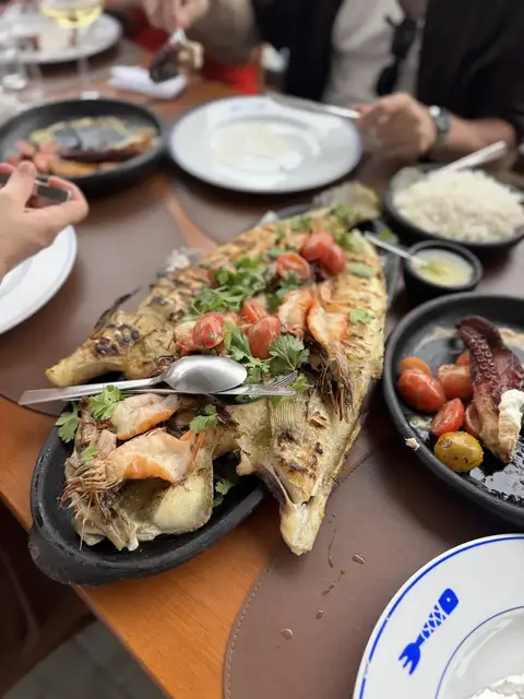 Peixe inteiro na brasa servido com acompanhamentos